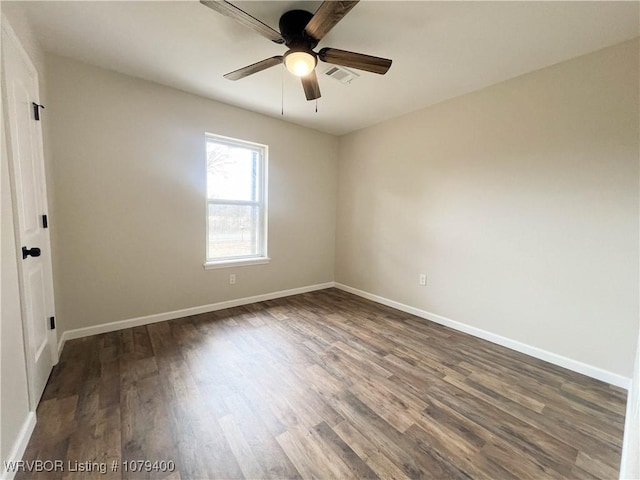 spare room with dark wood-style floors, visible vents, and baseboards