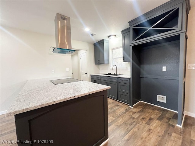 kitchen with extractor fan, a sink, wood finished floors, a peninsula, and black electric cooktop