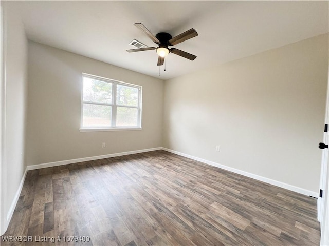 spare room with dark wood-type flooring, visible vents, ceiling fan, and baseboards