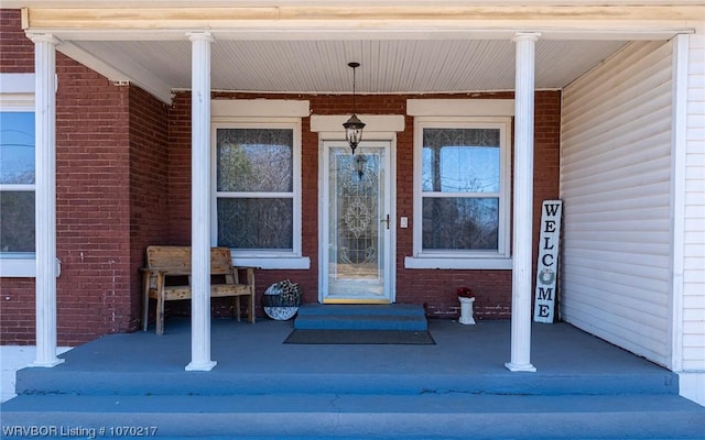 property entrance featuring covered porch and brick siding