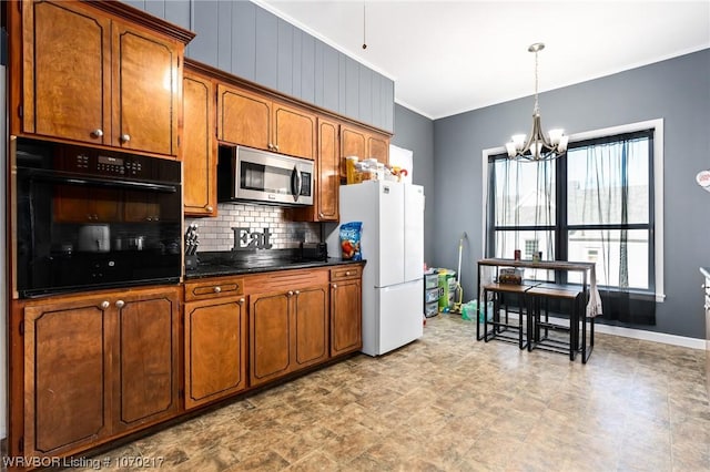 kitchen featuring black appliances, ornamental molding, a chandelier, dark countertops, and brown cabinetry
