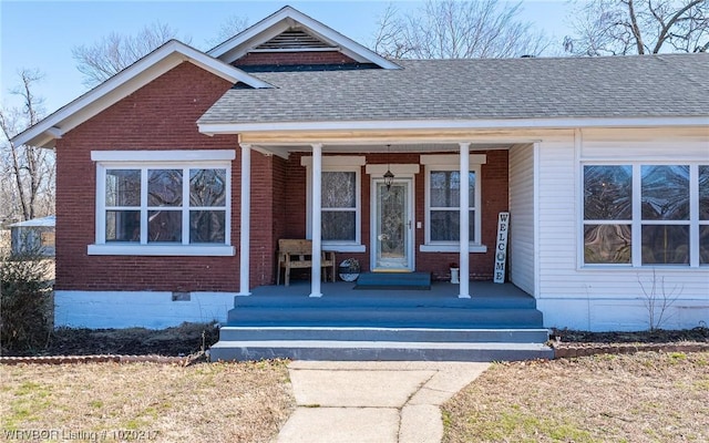 view of front of home with covered porch, brick siding, a shingled roof, and crawl space