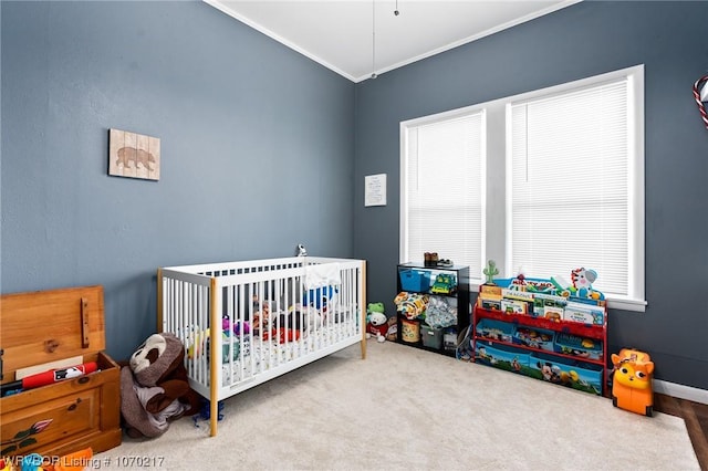 bedroom with ornamental molding, a nursery area, baseboards, and carpet flooring