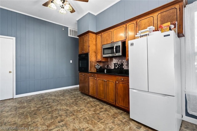 kitchen featuring stainless steel microwave, freestanding refrigerator, black oven, dark countertops, and ceiling fan