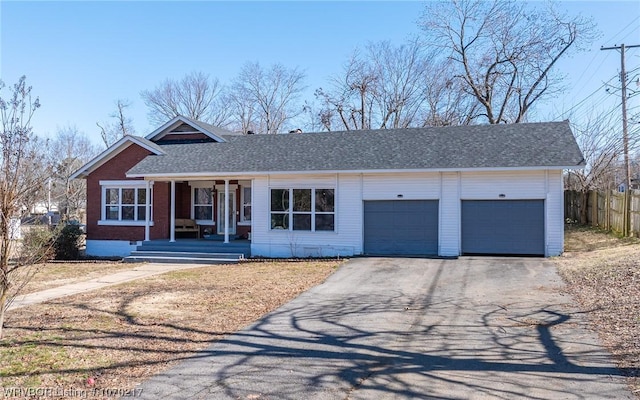 view of front of home with covered porch, driveway, an attached garage, and fence