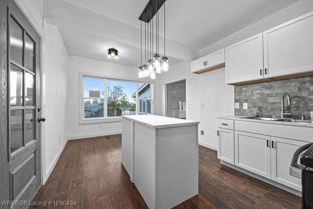kitchen with backsplash, white cabinets, dark wood-style flooring, and a sink