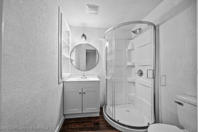 bathroom with a textured wall, a textured ceiling, and wood finished floors