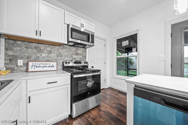 kitchen with white cabinets, stainless steel appliances, tasteful backsplash, light countertops, and dark wood-type flooring