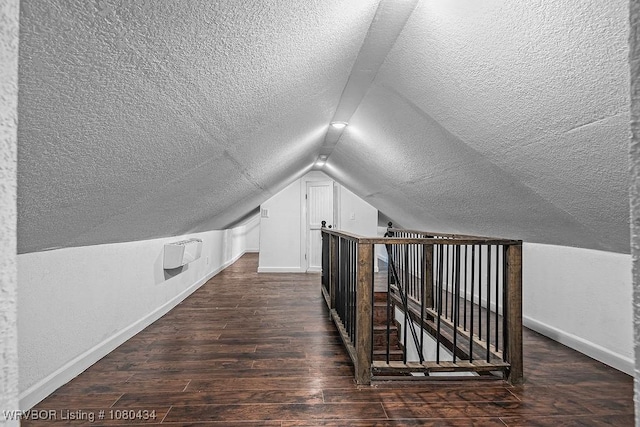 bonus room featuring lofted ceiling, baseboards, a textured ceiling, and dark wood-style flooring