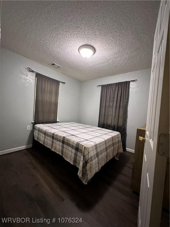 bedroom with dark hardwood / wood-style flooring and a textured ceiling