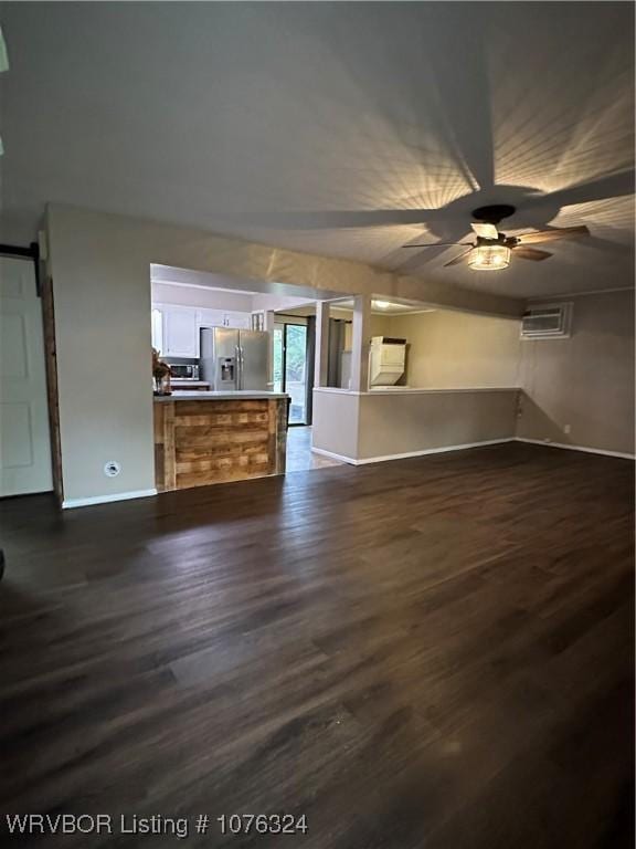 unfurnished living room featuring ceiling fan, dark hardwood / wood-style flooring, and a wall mounted air conditioner