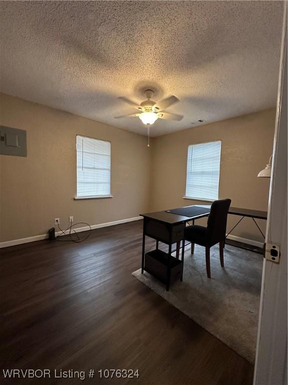 dining space with electric panel, ceiling fan, dark wood-type flooring, and a textured ceiling