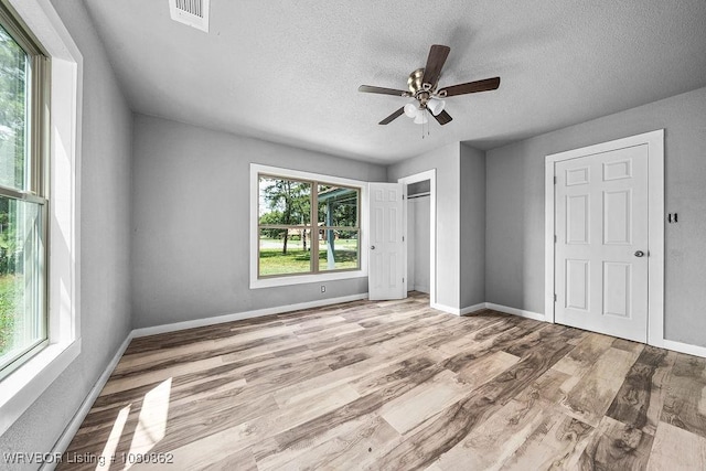 unfurnished bedroom with a textured ceiling, wood finished floors, baseboards, ceiling fan, and a closet