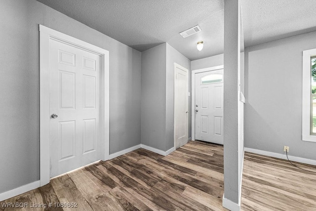 entryway with wood finished floors, baseboards, and a textured ceiling
