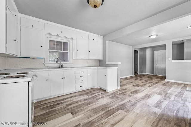 kitchen featuring electric stove, light countertops, white cabinets, light wood-style flooring, and a sink