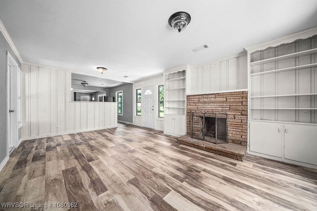 unfurnished living room featuring wood finished floors, a fireplace with raised hearth, and ornamental molding