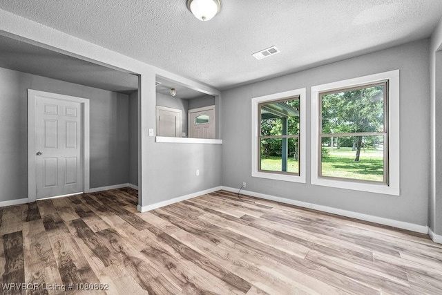 unfurnished room with wood finished floors, baseboards, and a textured ceiling