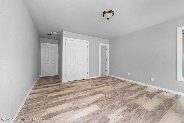 unfurnished bedroom with baseboards, wood finished floors, and a closet