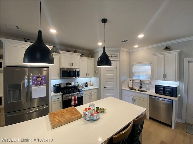 kitchen with stainless steel appliances, light countertops, visible vents, and a sink