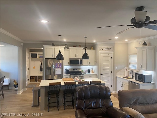 kitchen featuring light countertops, appliances with stainless steel finishes, open floor plan, white cabinets, and light wood-type flooring