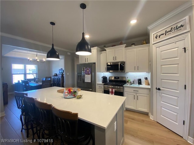 kitchen with ornamental molding, appliances with stainless steel finishes, light wood-style flooring, and white cabinets