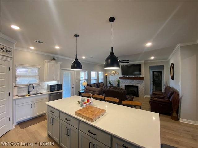 kitchen featuring visible vents, a sink, a fireplace, black microwave, and stainless steel dishwasher