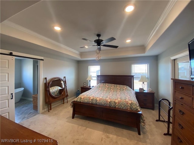 bedroom featuring light carpet, a barn door, a tray ceiling, and ornamental molding