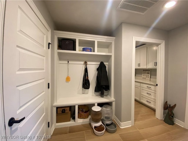 mudroom with wood finish floors, visible vents, and baseboards