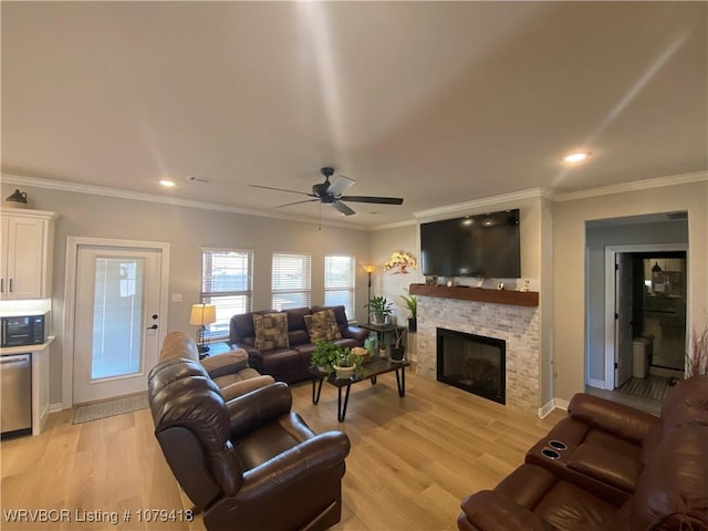 living area featuring visible vents, ceiling fan, crown molding, light wood-type flooring, and a fireplace