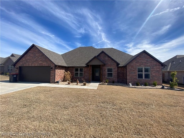 view of front of home featuring brick siding, a shingled roof, concrete driveway, an attached garage, and a front yard