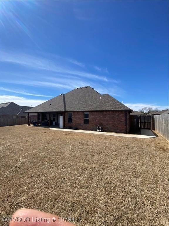 back of property featuring roof with shingles, a patio area, and fence