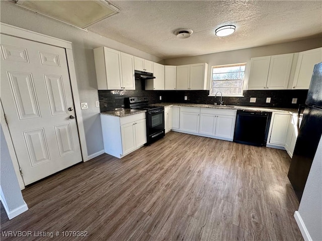 kitchen with a sink, under cabinet range hood, black appliances, and wood finished floors