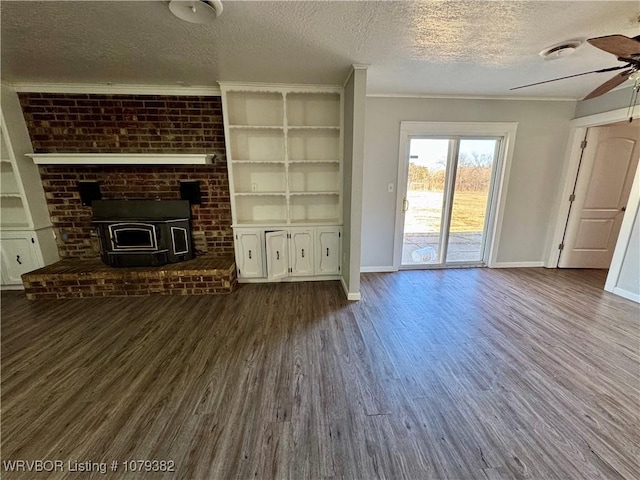 unfurnished living room featuring a textured ceiling, dark wood-type flooring, a ceiling fan, baseboards, and ornamental molding