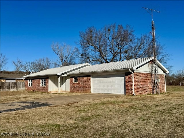 view of home's exterior with metal roof, brick siding, fence, driveway, and a yard