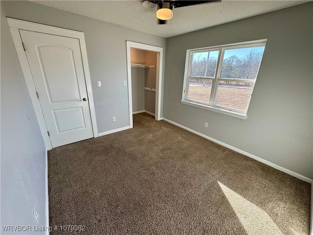 unfurnished bedroom featuring a textured ceiling, a ceiling fan, baseboards, a closet, and dark carpet