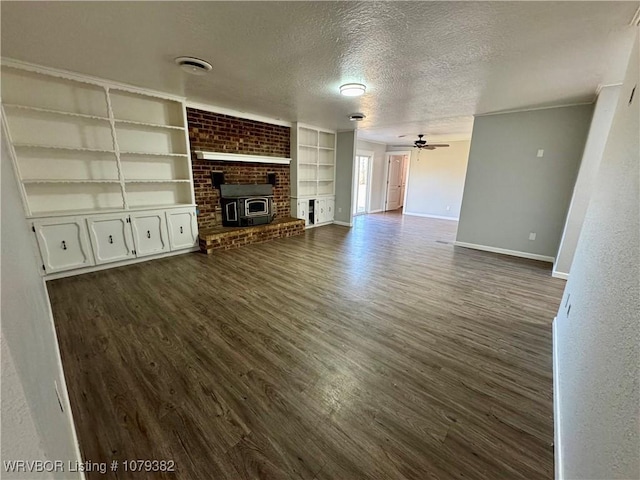 unfurnished living room featuring a textured ceiling, ceiling fan, dark wood finished floors, and baseboards