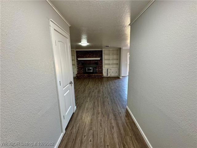 hall featuring dark wood-style floors, baseboards, a textured ceiling, and a textured wall