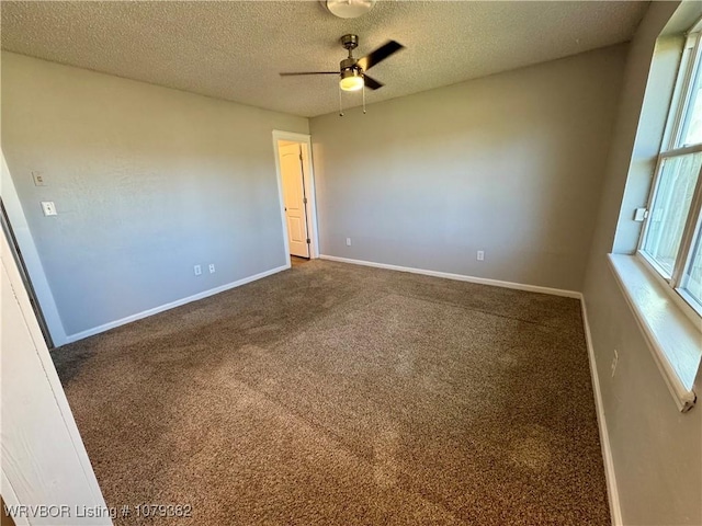 empty room with ceiling fan, a textured ceiling, baseboards, and carpet flooring