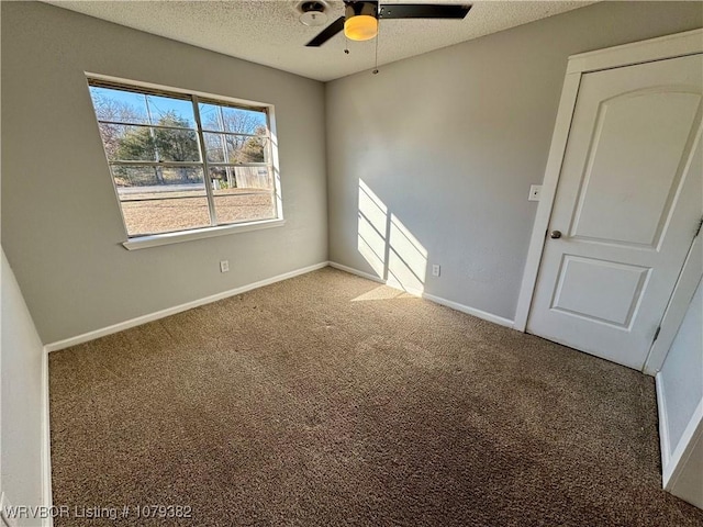 carpeted spare room with a ceiling fan, baseboards, and a textured ceiling