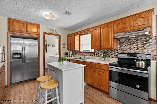 23 Wild Rose Ln, Booneville, AR 72927 - kitchen featuring appliances with stainless steel finishes, washer and dryer, under cabinet range hood, light countertops, and light wood-style floors