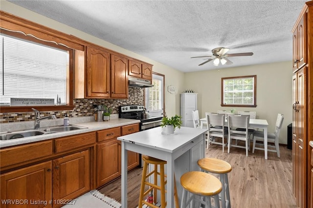 23 Wild Rose Ln, Booneville, AR 72927 - kitchen with stainless steel range with electric stovetop, a ceiling fan, brown cabinetry, light countertops, and a breakfast bar area