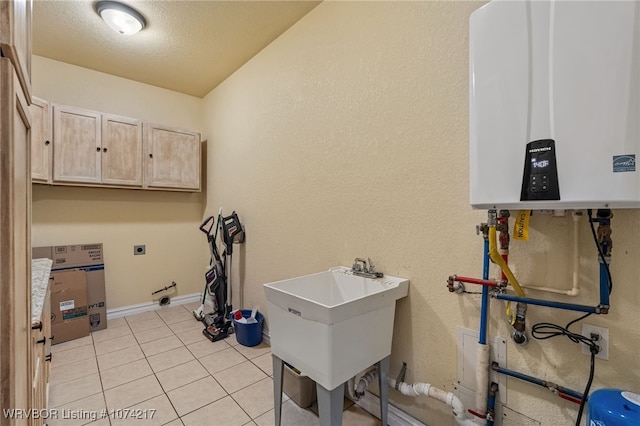 clothes washing area featuring cabinets, tankless water heater, sink, light tile patterned floors, and hookup for an electric dryer