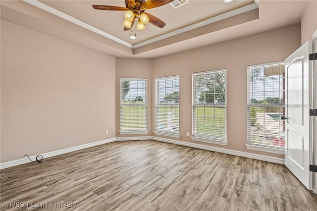 empty room featuring ceiling fan, light hardwood / wood-style floors, a raised ceiling, and ornamental molding