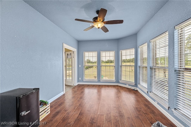 empty room featuring a textured ceiling, ceiling fan, and dark wood-type flooring