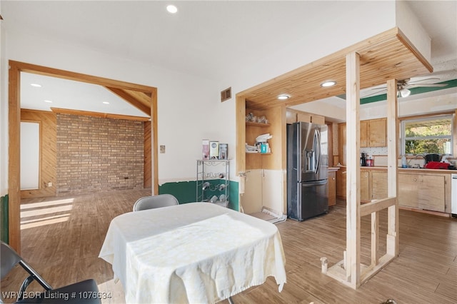 bedroom with stainless steel fridge, hardwood / wood-style floors, and brick wall