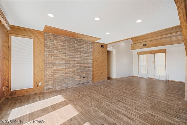 unfurnished living room with hardwood / wood-style floors, brick wall, and wooden walls