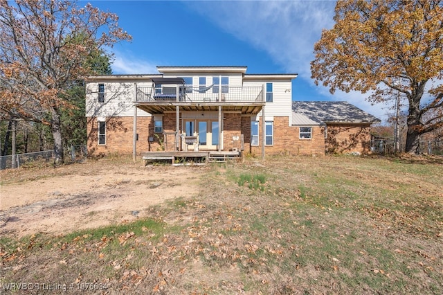 rear view of house featuring a lawn, a balcony, and a wooden deck