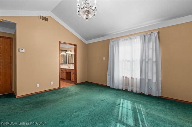 carpeted empty room featuring a chandelier and vaulted ceiling