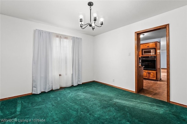 carpeted spare room with a notable chandelier