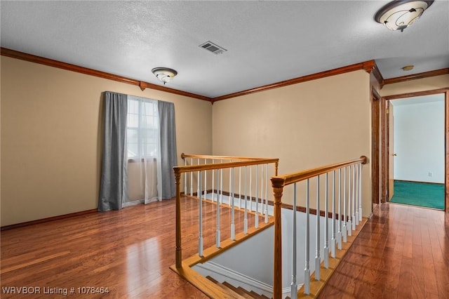 hallway featuring a textured ceiling, ornamental molding, and hardwood / wood-style flooring